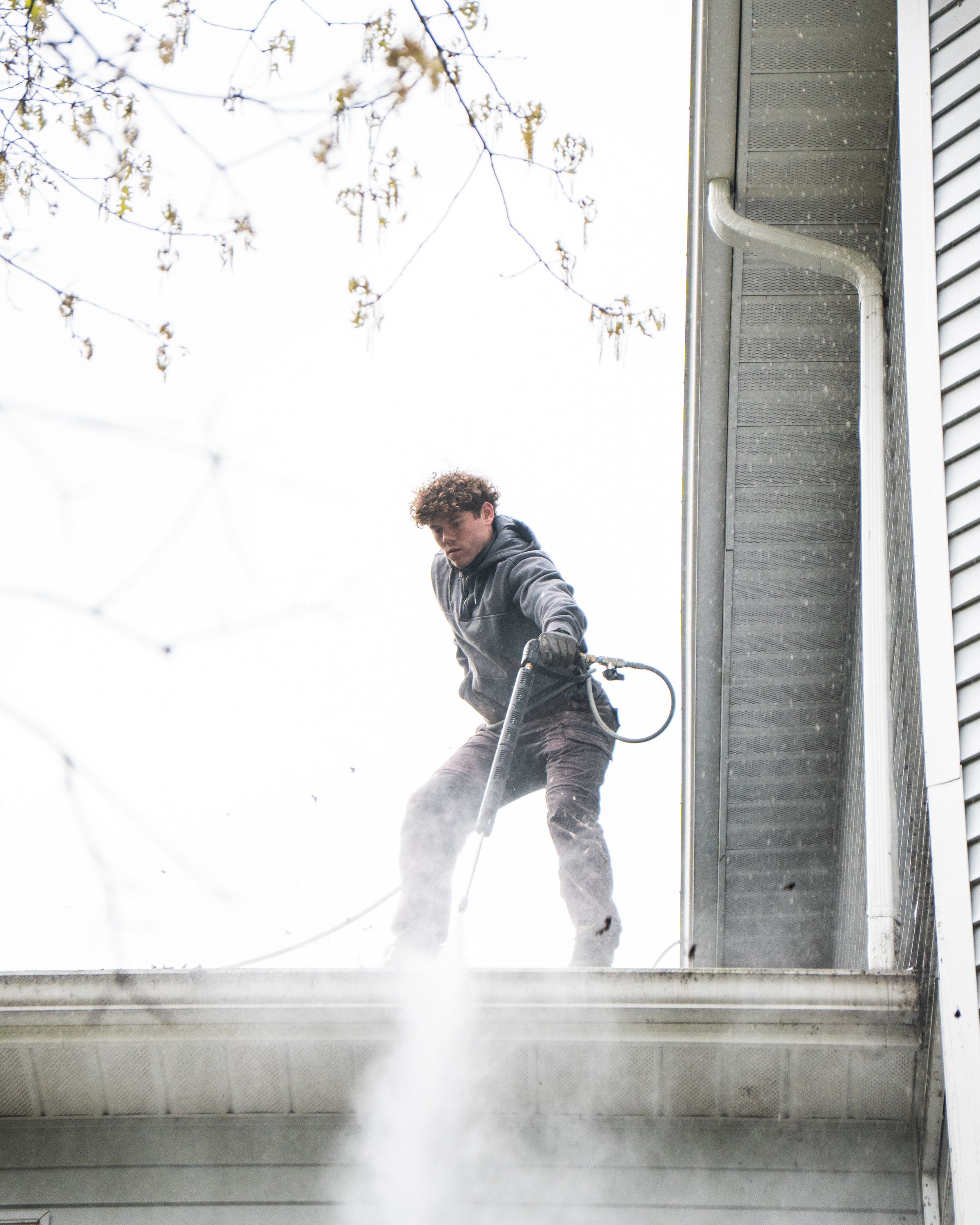 Elevation technician flushing a downspout and watching it run clear at the bottom