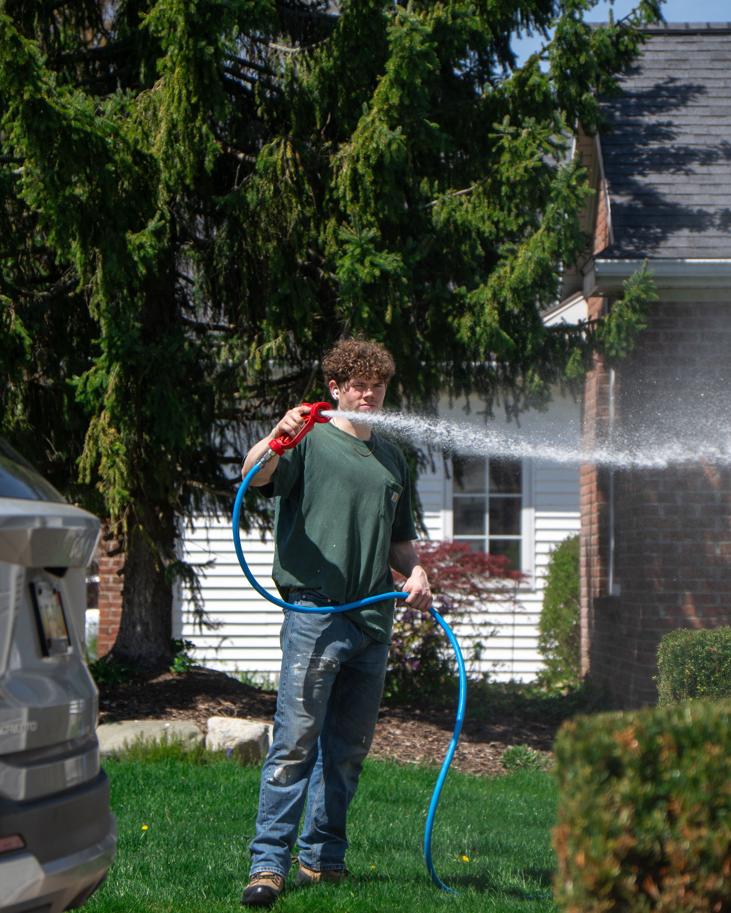 Elevation technician soft-washing the brick and siding of a two-story home at low pressure