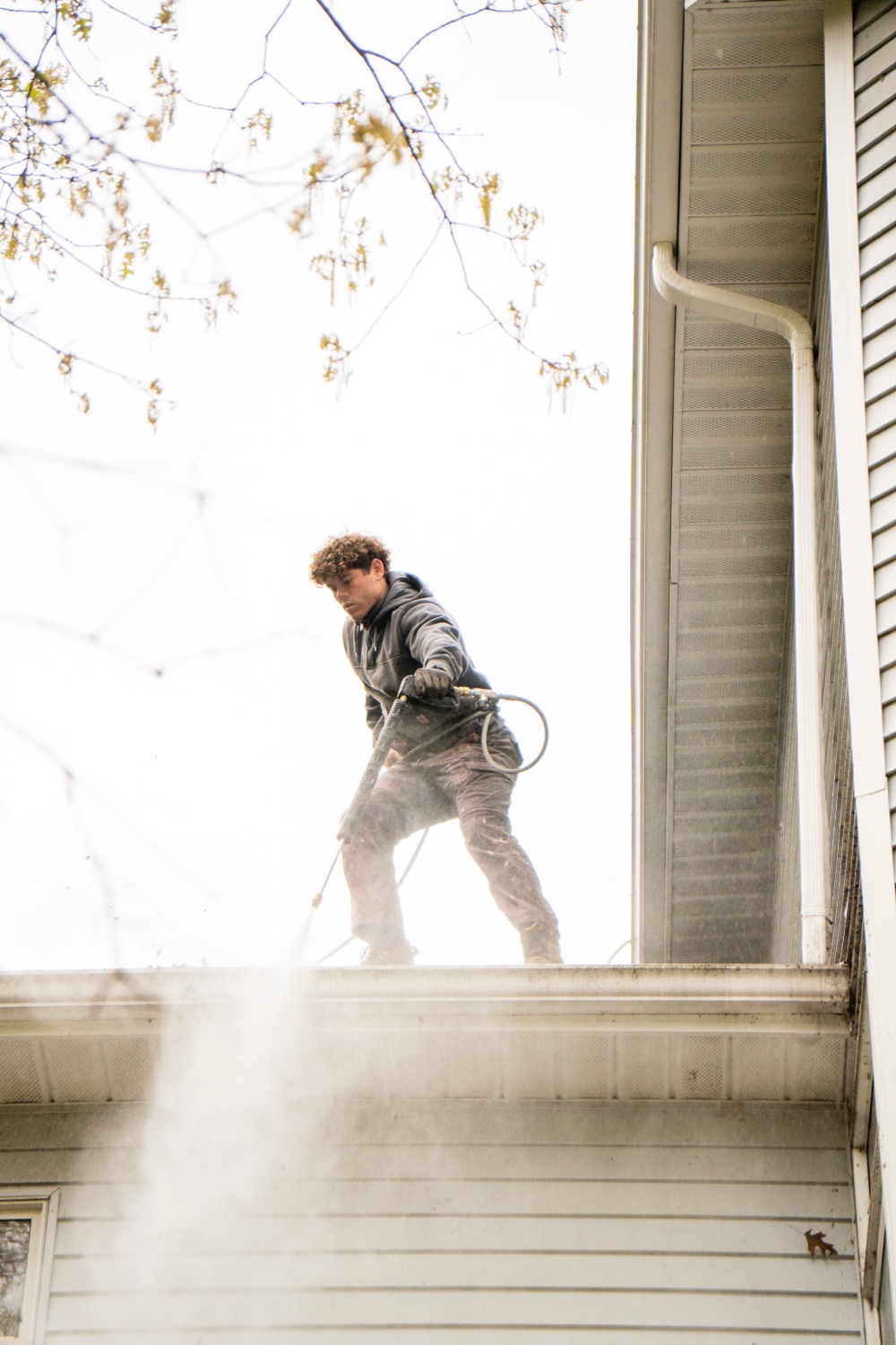 Elevation crew soft-washing a second-story roofline in the Grand Rapids metro